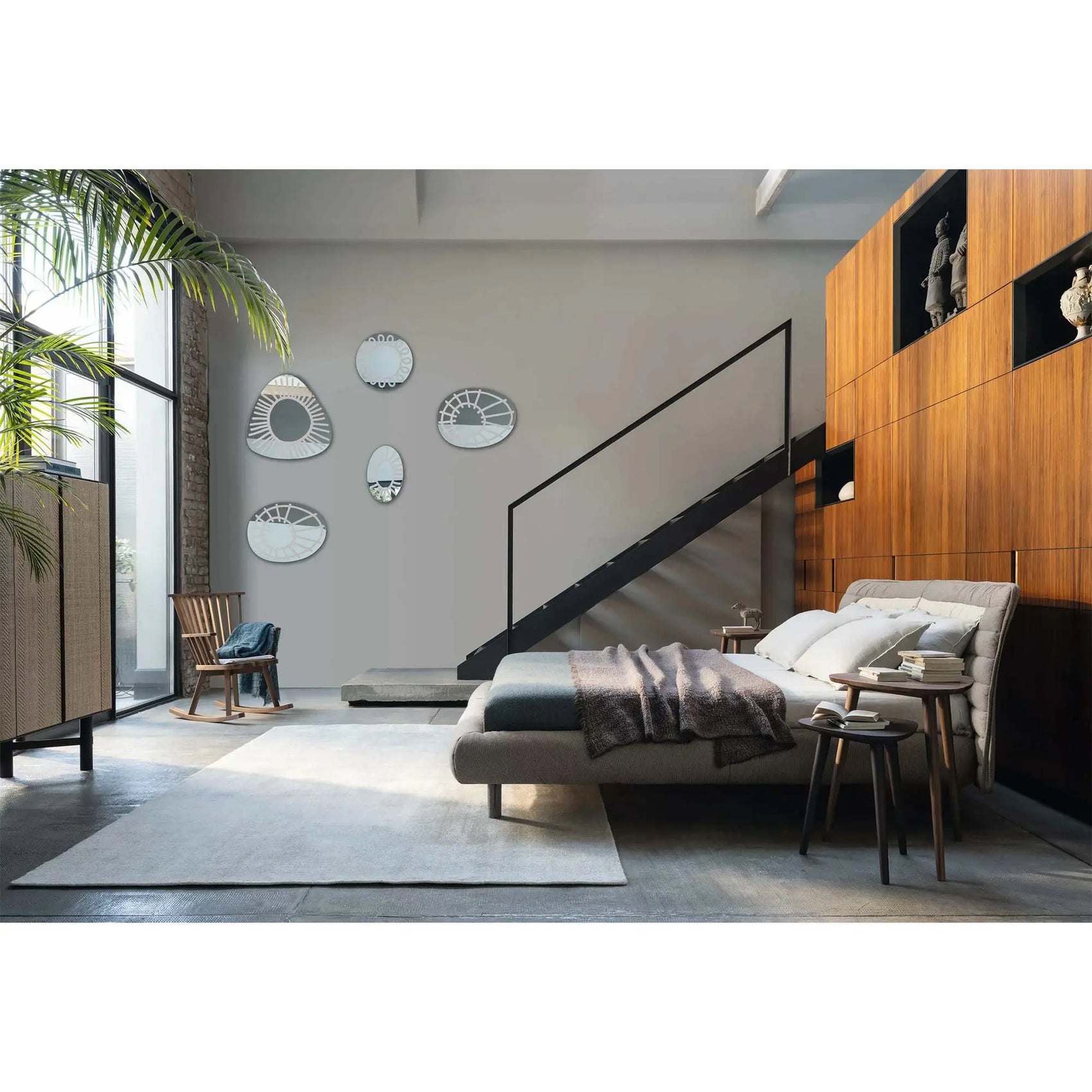 Gervasoni Plumeau Bed in bedroom. Pictured with staircase in background and end tables with books (side view). Upholstered Bed Frames and Headboards USA.